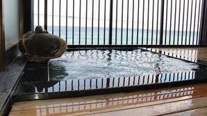 A stone sculpture on a wet wooden platform with a view of the sea through a black metal railing. - Hotel & Resort Izunone (Higashiizu)