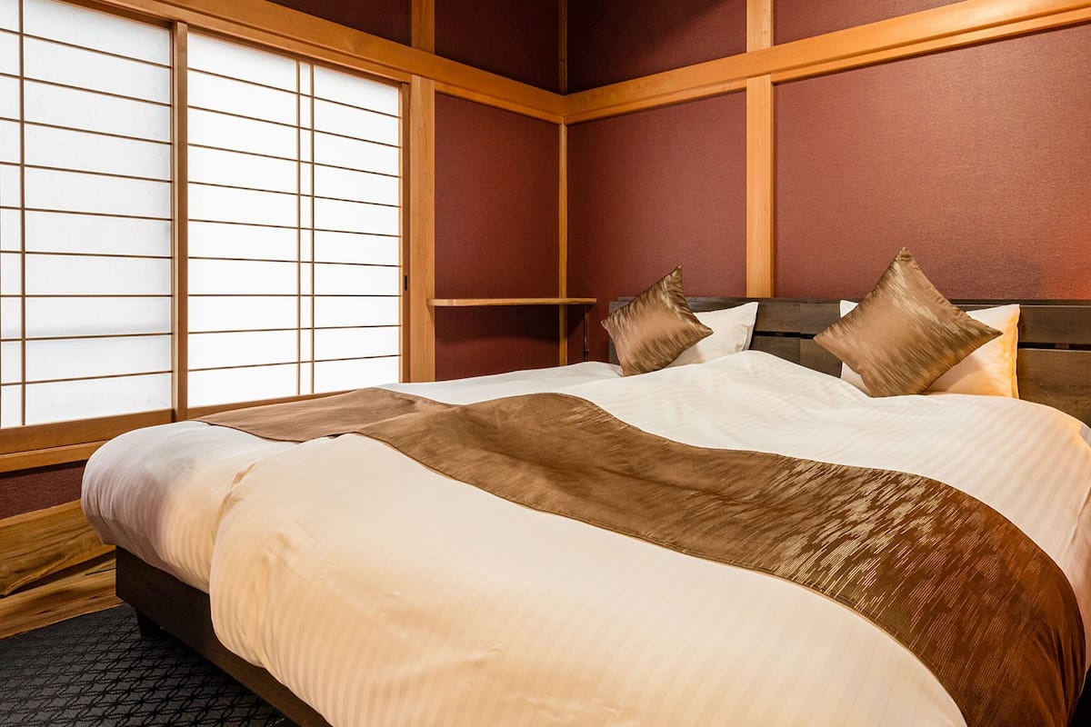 Een hotelkamer met een bed, een houten hoofdeinde en een nachtkastje met een lamp.