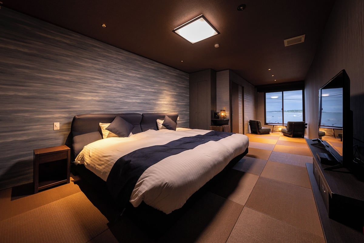 Een moderne hotelkamer met een groot bed, een televisie en uitzicht op zee.