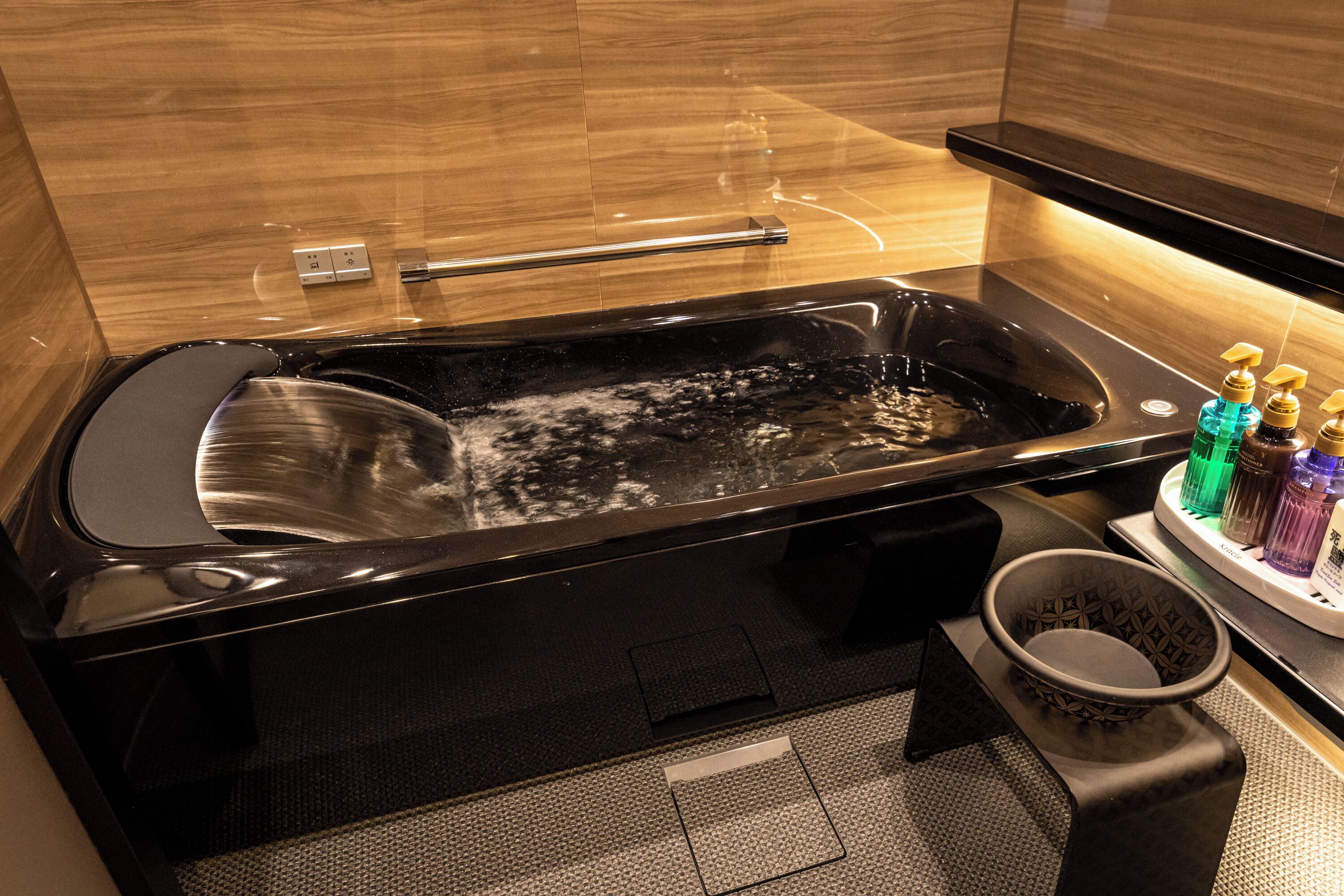 A modern bathroom with a black bathtub, a glass-enclosed shower, and a small sink area.