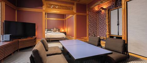 A hotel room with a bed, a TV, a sofa, a table, and a patterned floor.