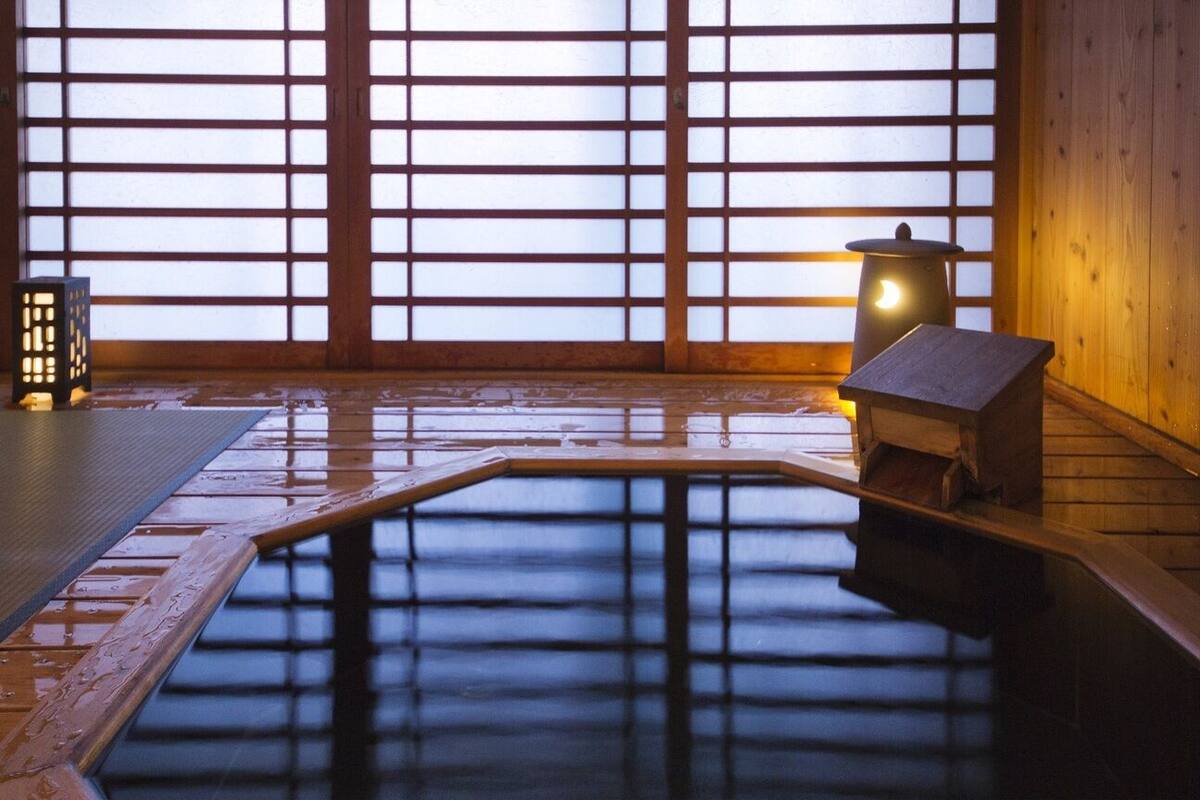 Een traditioneel Japans onsen met een houten vloer, een houten bankje en een kleine lantaarn.