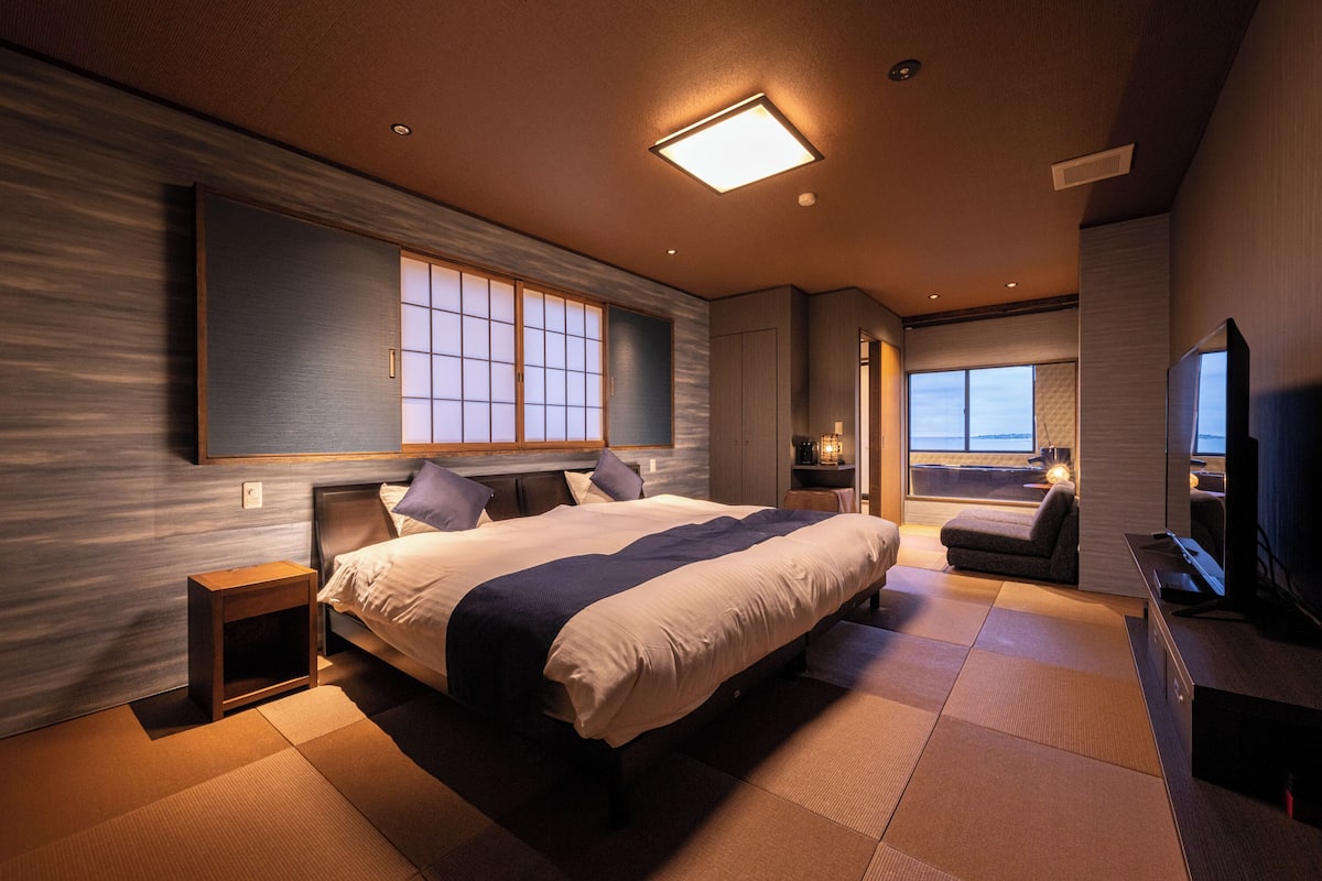Een moderne hotelkamer met een groot bed, een televisie en uitzicht op de stad.