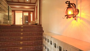 A hotel lobby with a staircase leading to a room entrance, a wall-mounted luggage storage unit, and a decorative wall light. - Hotel Ryuo Village (Yamanouchi)