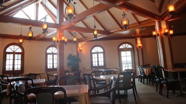 A dining area with multiple tables and chairs, wooden beams on the ceiling, and hanging light fixtures. - Hotel Ryuo Village (Yamanouchi)