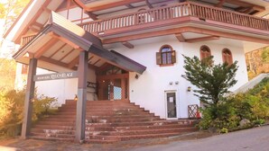 A two-story building with a balcony, a staircase leading to the entrance, and a sign reading "Resort Hotel RyovoVillage". - Hotel Ryuo Village (Yamanouchi)