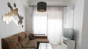 Una sala de estar moderna con un sofá modular, una mesa de centro, un televisor sobre un mueble bajo y un elemento decorativo en la pared.