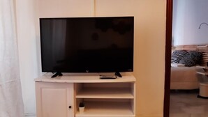 Un mueble blanco de entretenimiento con un televisor de pantalla plana, un control remoto y un estante pequeño.