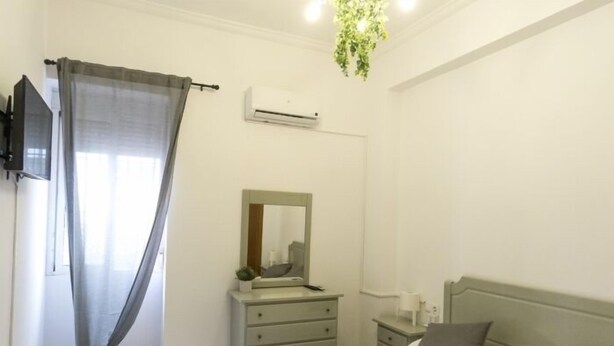 Un dormitorio con cama, cómoda, espejo, inodoro y televisor.