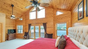 A spacious bedroom with a large bed, a ceiling fan, and a view of a lake through large windows. - Dog Friendly Townhome w/ Deck & Sunset Views (McHenry)