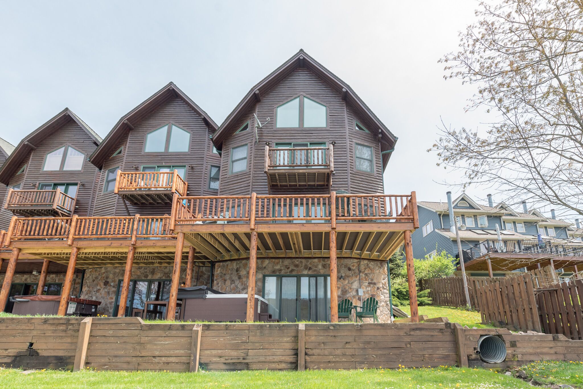 A multi-story wooden house with balconies, a stone foundation, and a covered outdoor area. - Dog Friendly Townhome w/ Deck & Sunset Views (McHenry)
