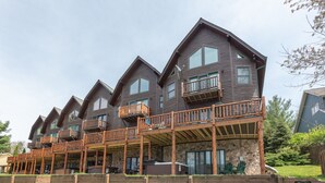 A row of wooden multi-story buildings with balconies and a stone facade. - Dog Friendly Townhome w/ Deck & Sunset Views (McHenry)