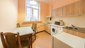 Una cucina compatta con tavolo, sedie, lavatrice, forno a microonde e lavello.