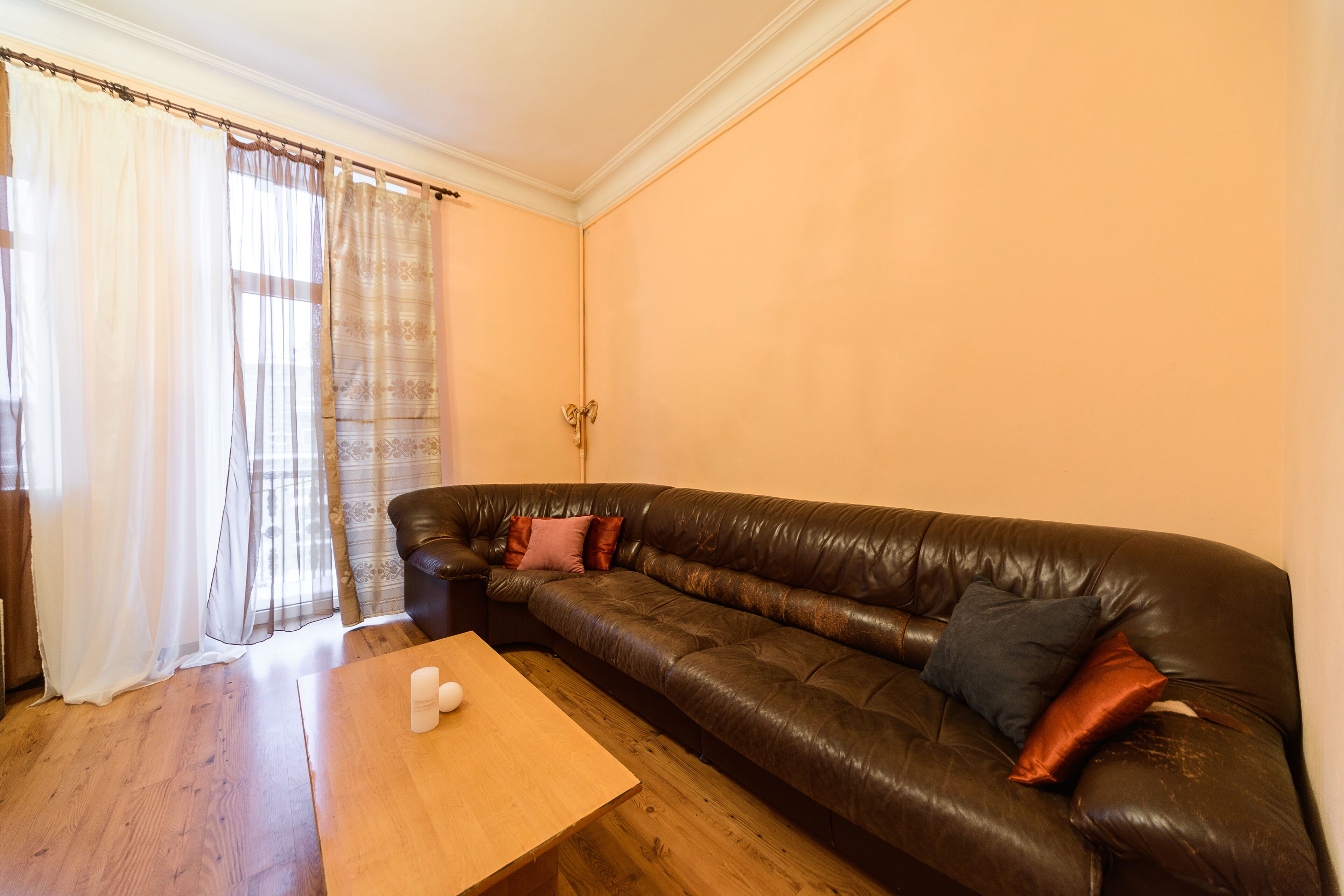 A living room with a brown leather sofa, a wooden coffee table, and a door with a golden handle.