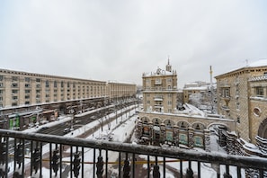 A snow-covered cityscape with historic buildings and a central monument.