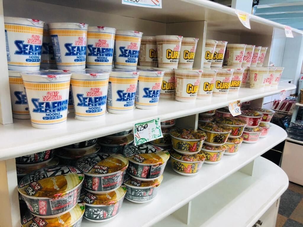 A variety of packaged food items on shelves, including seafood noodles and other packaged meals.