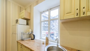 A kitchen with a sink, countertop, cabinets, and a window with a view of buildings. - Apartments Kreshchatik 17-21 (Kyiv)