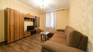 A living room with a sofa, TV, wooden cabinet, and a small table. - Apartments Kreshchatik 17-21 (Kyiv)