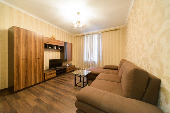 A living room with a sofa, TV, wooden cabinet, and a small table.