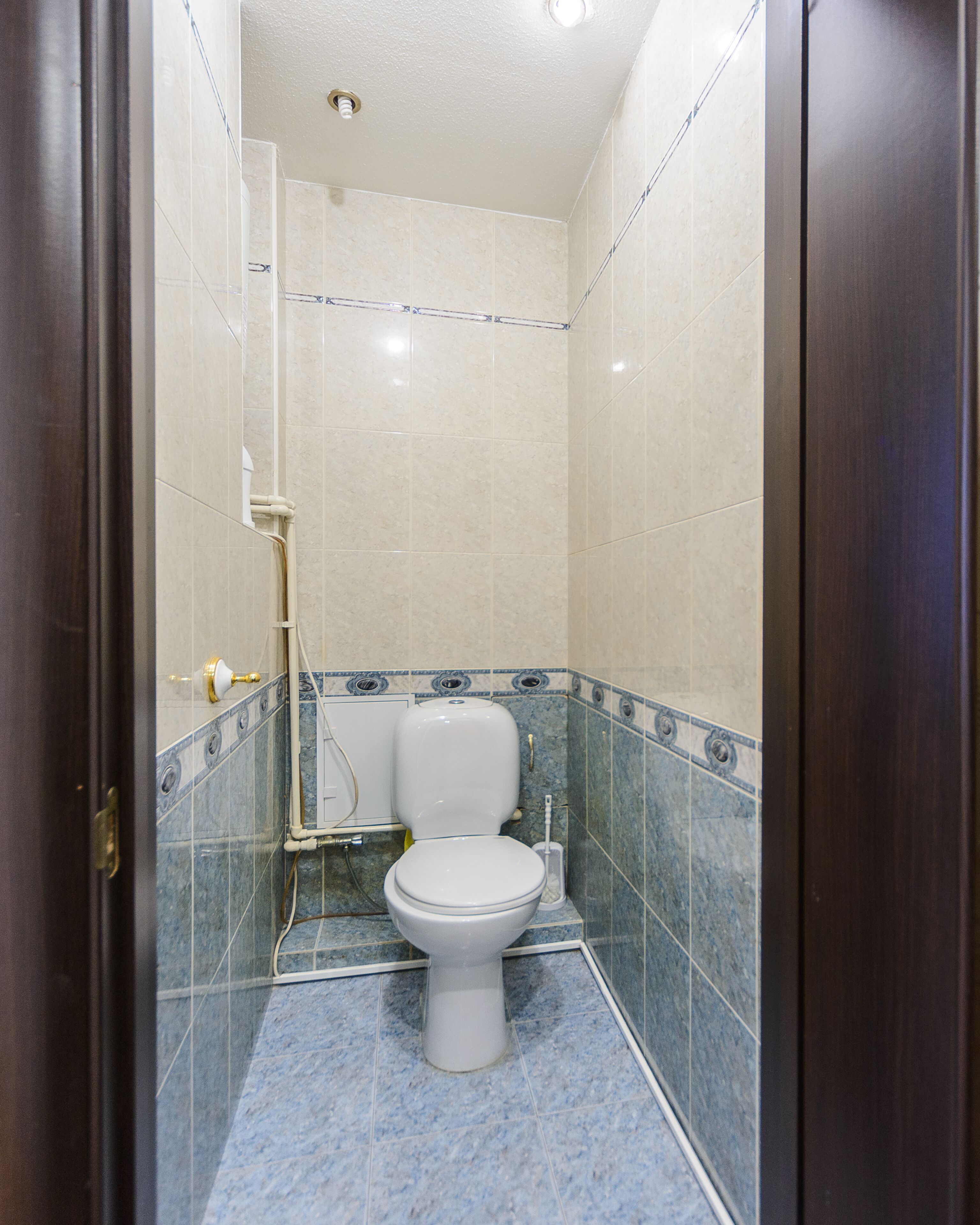 A small, tiled bathroom with a toilet, a shower, and a sink.