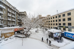 A snowy urban street with multi-story buildings, a McDonald's, and a Pepsi truck.