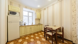 A kitchen with a window, a table with chairs, and a refrigerator. - Apartments Kreshchatik 17-21 (Kyiv)
