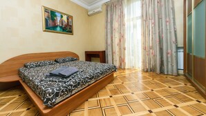 A bedroom with a bed, a painting on the wall, and a window with curtains. - Apartments Kreshchatik 17-39 (Kyiv)