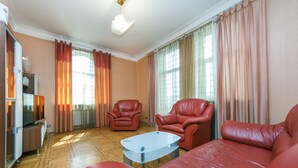 A living room with a red leather sofa, two red leather armchairs, a glass coffee table, a television, and a wooden parquet floor. - Apartments Kreshchatik 17-39 (Kyiv)