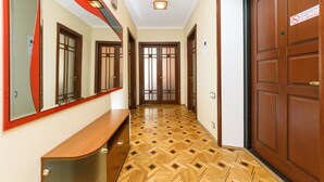 A hallway with wooden doors, a bench, and a patterned floor. - Apartments Kreshchatik 17-39 (Kyiv)