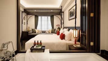 Habitación de hotel con una cama grande, una mesita de noche, una ventana con cortinas, un cuadro en la pared y un baño con bañera.