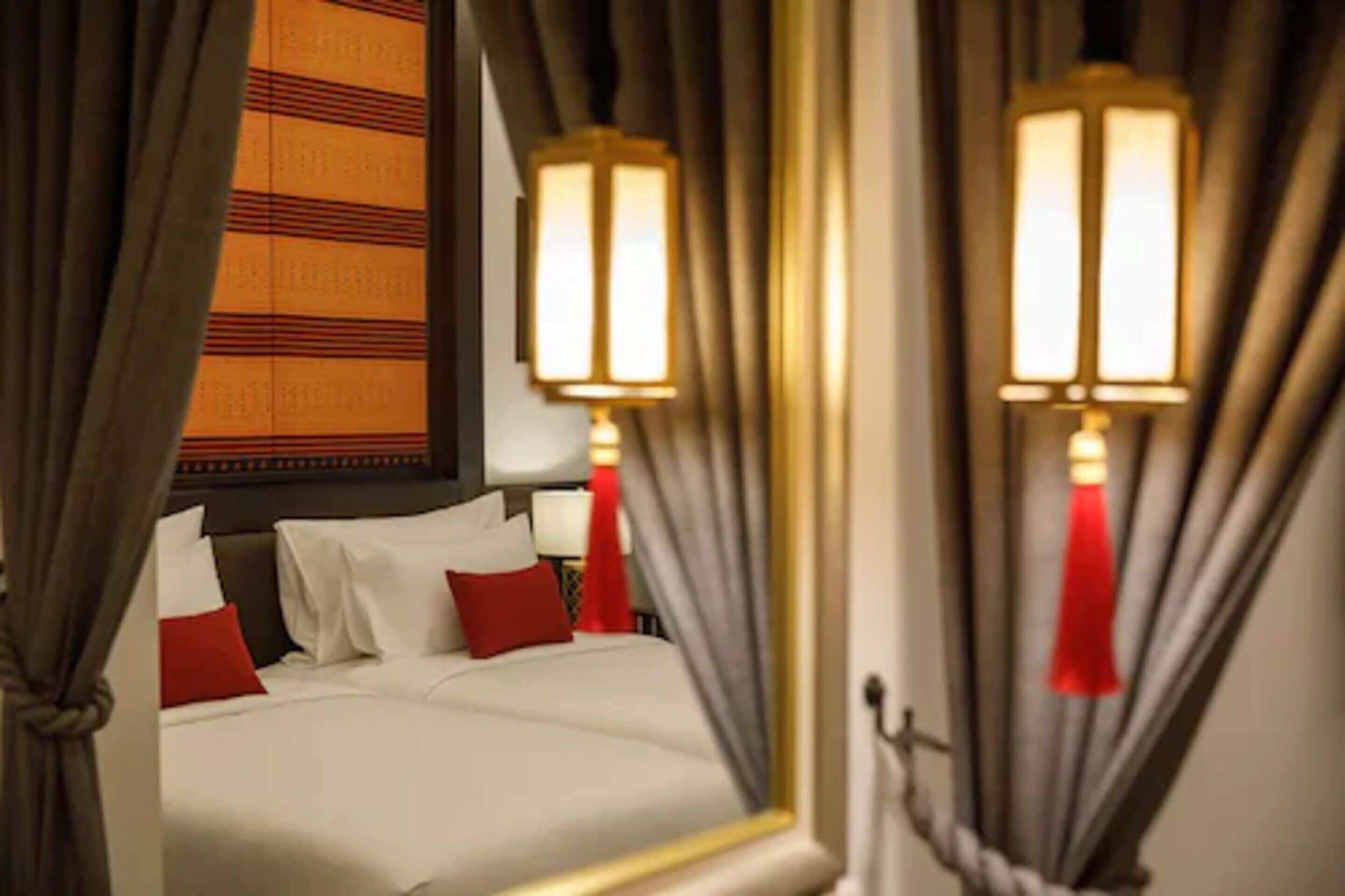 Une chambre d  ’hôtel avec un lit, des rideaux et des lampes fixées au mur.