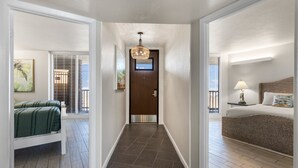 Un couloir d’hôtel avec un lit à droite, un banc à gauche et une porte au fond.