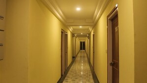 A hotel hallway with doors on both sides, a tiled floor, and a ceiling with recessed lighting. - Hotel Niladrii Galaxy (Siliguri)
