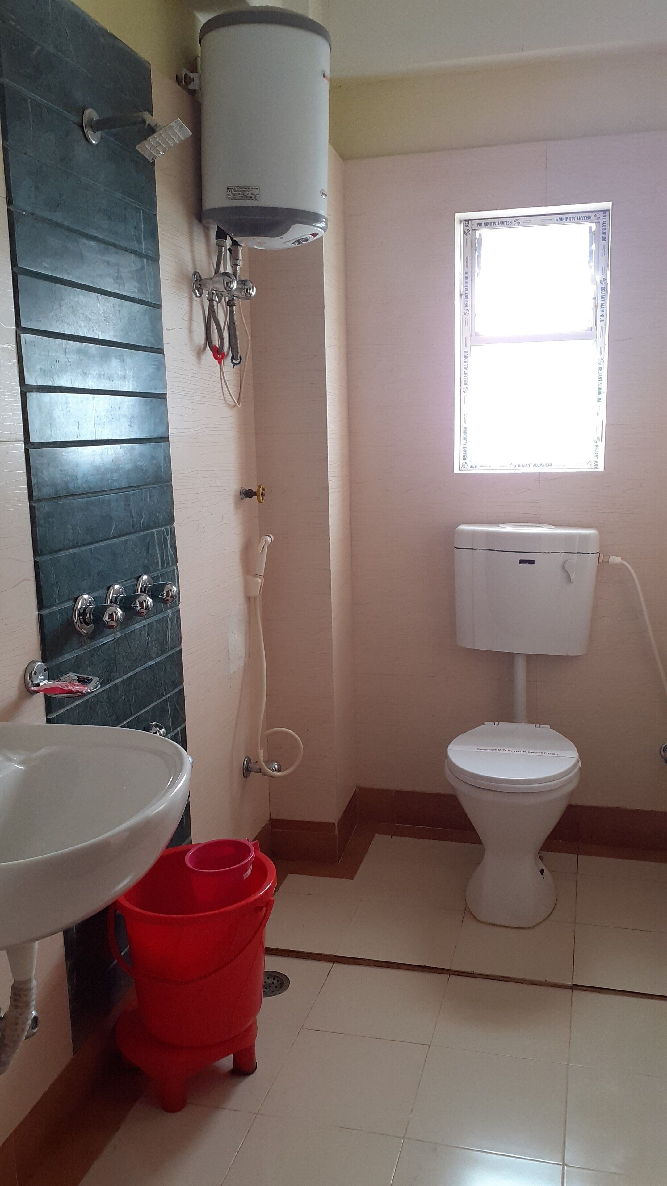 A bathroom with a toilet, a sink, a shower, and a window.