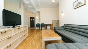 A living room with a flat-screen TV, a sofa, a coffee table, and a desk with two chairs. - Apartments Kreshchatik 27-47 (Kyiv)