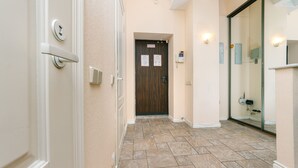 A hallway with a wooden door, a light switch, and a wall-mounted light fixture. - Apartments Kreshchatik 27-47 (Kyiv)