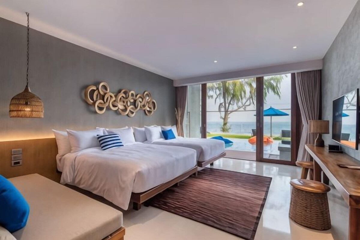 Una habitación de hotel moderna con una cama grande, un sofá, un televisor y vistas al exterior.