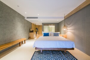 Un dormitorio moderno con una cama grande, un banco y una alfombra estampada.