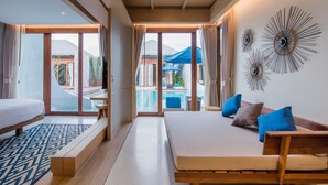 A modern hotel room with a large bed, a desk, and a view of a pool and outdoor area. - Lullaby The Sea Hua Hin (Cha-am)