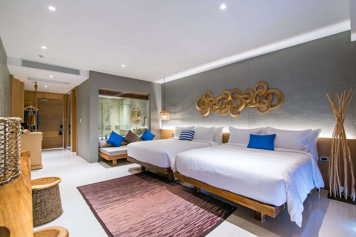 Una habitación de hotel moderna con dos camas, un espejo grande y un adorno en la pared.