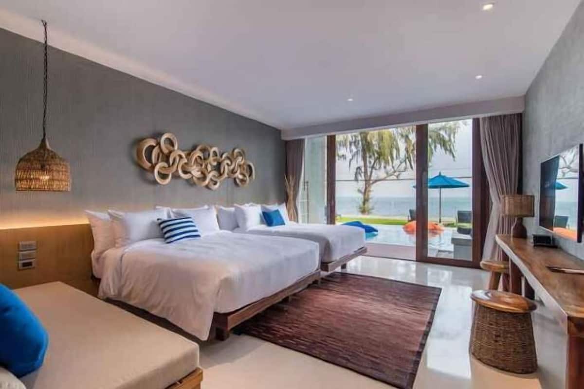 Una habitación de hotel moderna con dos camas, un ventanal con vistas, un televisor de pantalla plana y una lámpara de techo tejida.