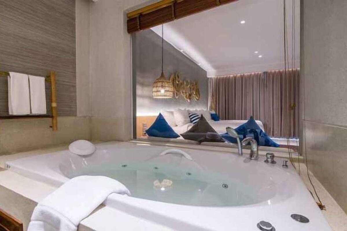 Ein modernes Badezimmer mit einer großen Badewanne, einer Duschkabine und einem Spiegel, der den Raum reflektiert.