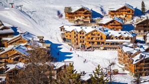 Een wintersportgebied met houten chalets, een skilift en een besneeerd landschap.