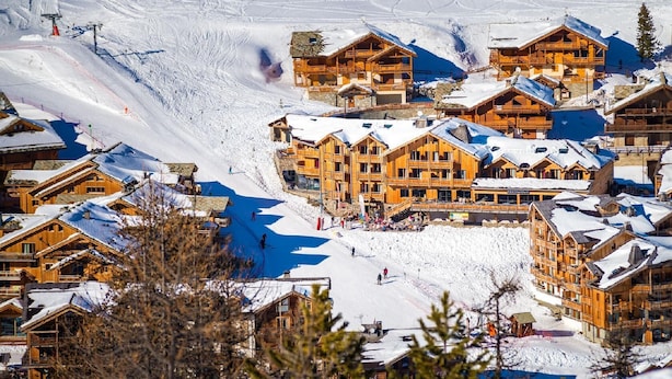 Un centro de esquí con cabañas de madera, un telesilla y un paisaje cubierto de nieve.