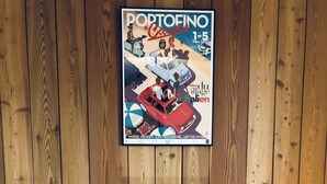 Una esquina de una habitación con un muro de madera y un cartel de un coche antiguo.