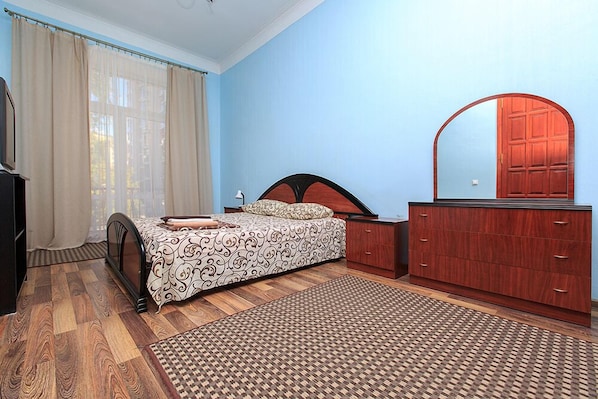 A bedroom with a bed, a dresser, a mirror, and a window with curtains.