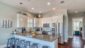 A spacious kitchen with white cabinets, a granite countertop, stainless steel appliances, and a central island with bar stools. - HEAVENLY VIEW: Spacious & Beautiful 30A Home with Pool, Huge Deck, Steps to Beach! (Santa Rosa Beach)