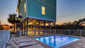 A swimming pool with lounge chairs, a covered deck, and a building with a green exterior. - HEAVENLY VIEW: Spacious & Beautiful 30A Home with Pool, Huge Deck, Steps to Beach! (Santa Rosa Beach)