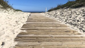 Un paseo marítimo de madera que conduce a una playa con cielos despejados.