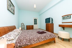 A bedroom with a bed, a dresser, a television, and a door. - Apartments Kreshchatik 27-28 (Kyiv)